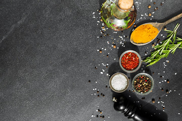 On a stone black spice surface, on a wooden spoon of turmeric, in glass pialls salt, paprika, dried...