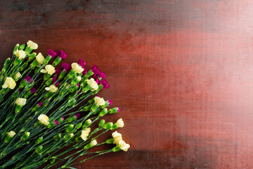 Fresh carnation flowers on abstract background of a wooden table