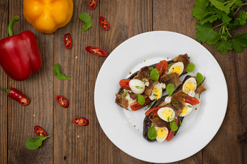 Baked eggplant with bacon, garlic and quail eggs. Wooden background. Top view. Close-up
