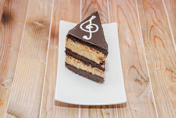 Chocolate slice cake with caramel cream, ornate with key sol, white plate