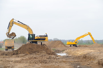 Obraz premium Construction site with big yellow excavators digging an piles of sand