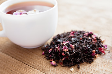 Cup of  herbal tea with rose petals. Wooden background.