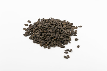Black fried sunflower seeds on a white background.