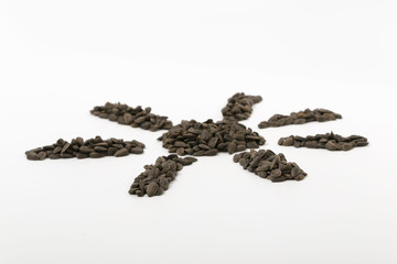 Black fried sunflower seeds on a white background.