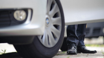 Business man's feet standing next to the car, in the open doorway of the grey car