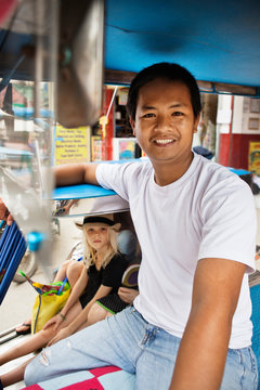Smiling pedicab driver with passengers