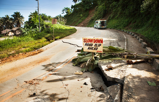 Cracks in road with warning sign