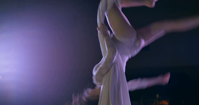 Woman dancer on white aerial silk, aerial contortion.