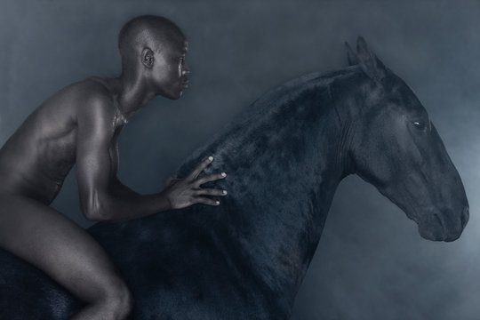 Nude man riding black horse