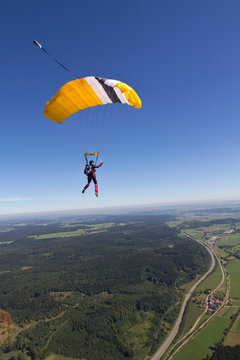 Woman skydiving over rural landscape