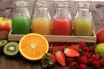 several bottles with fruit and berry juices smoothies and milkshakes , vintage wooden background, selective focus