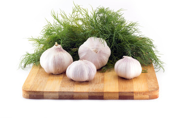 Still life of garlic on a wooden board with dill on white background