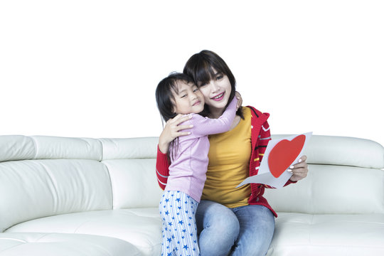 Child hugging her mom on sofa