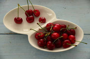 Mavi  zemin üzerinde beyaz kasede  kirazlar