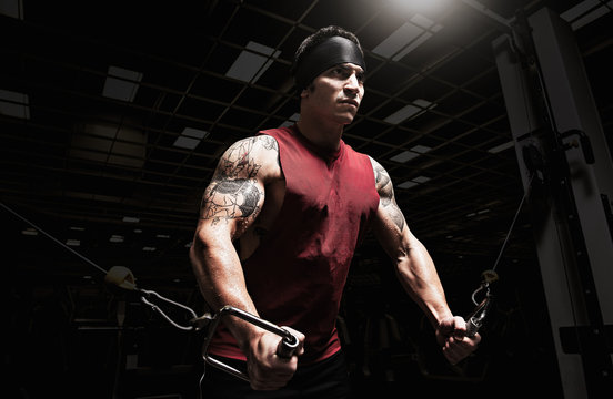 Muscular young man performing pulldown exercises in gym
