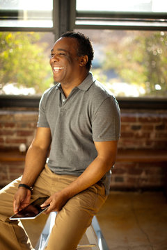 Man posing with charismatic smile holding digital tablet