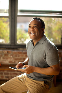 Man posing with charismatic smile holding digital tablet