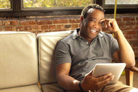 Man posing with charismatic smile holding digital tablet
