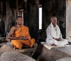 Senior and young monk meditating in temple in Angkor Wat, Siem Reap, Cambodia