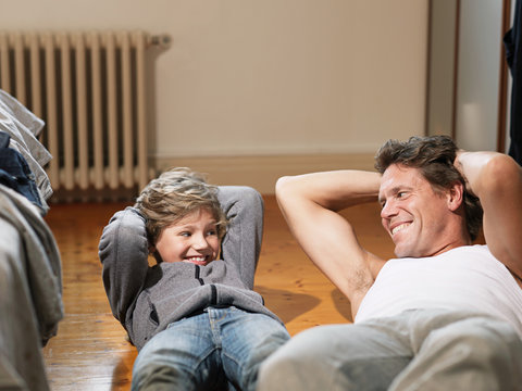 Mature man and son performing exercises in bedroom