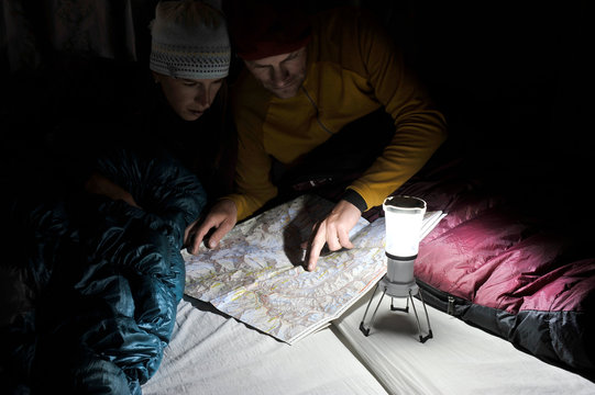 Couple in sleeping bags, looking at trail map, Yak Kharka, Nepal