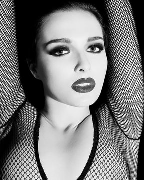Young woman wearing fishnet outfit, arms raised