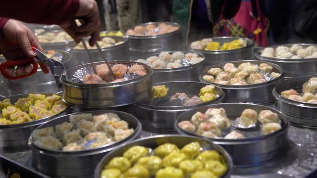 4K Vendor preparing and selling Shaomai and customers at Asian Street Food Market in Taiwan. Dumpling is a chinese traditional food at Oriental Night Market. Restaurant in downtown-Dan