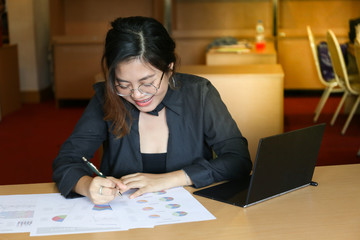 Fototapeta na wymiar working woman in black dress look happy to see charts paper on wooden desk