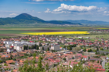 Fototapeta na wymiar Spring view over Rasnov city, in Brasov county (Romania), with Codlea mountain in the background and with Cristian village in the far right