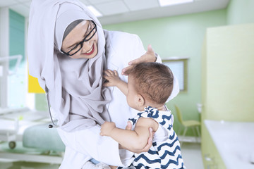 Muslim pediatrician examining a baby