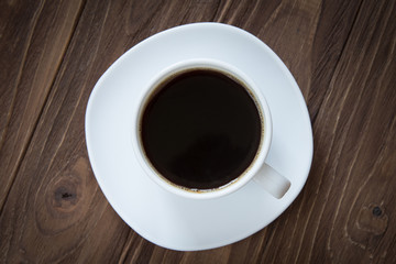 Cup of coffee on brown wooden background top view