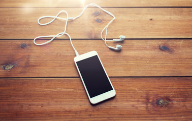 close up of blank smartphone and earphones on wood