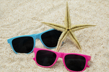 Two sunglasses and starfish on sand