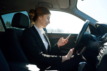 Mid-age business woman working while being in the car