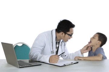 Obraz premium Young pediatrician checks tongue of his patient