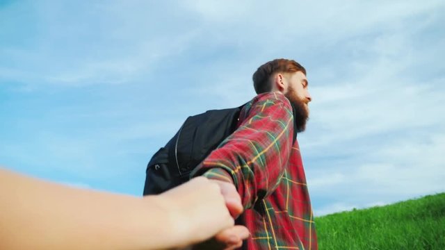 A young bearded man helps climb a mountain friend. Helping hand.