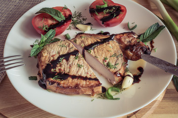 Vintage tone. Cut pork steak with sauce, mint, garlic and sliced tomato