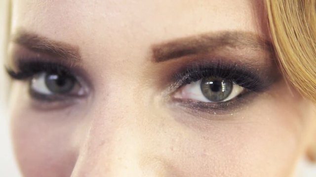 Closeup view of makeup applied on eyes of a model. Model with flase eyelashes opening her eyes and looking in the camera. Professional makeup. Slowmotion shot