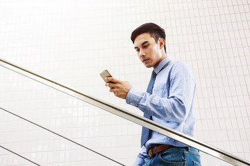 Young Asian businessman read message in Smart phone with seriously face at stair