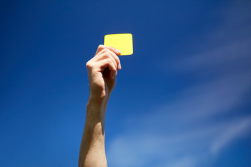 referee on football field showing yellow card