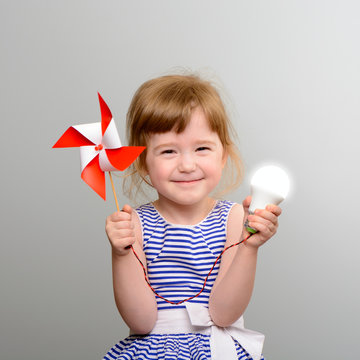 The concept of renewable energy. Cute girl with led light bulb and windmill