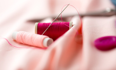 sewing needle, spools of thread and cloth