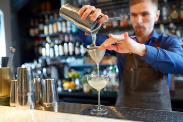 bartender with shaker preparing cocktail at bar