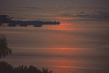 Reflection of the sunset in the waters of the Arabian Sea against the background of fishing boats