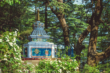 Buddhist stupa against the background of green trees - obrazy, fototapety, plakaty
