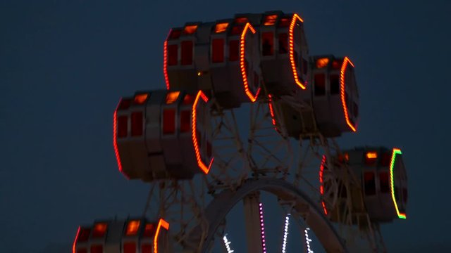 Close-up of Ferris wheel, by rotating at night with large colorful of led light in motion.