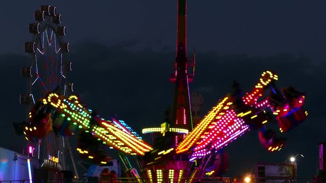 Attractions of fair, with colorful lights and moving at sunset.