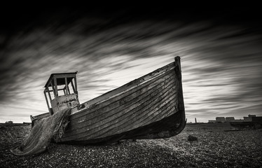 Fototapeta na wymiar Fishing boat stranded on a pebbled beach. Dungeness, England