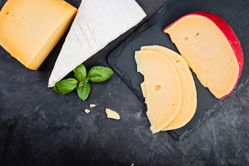 Different  types of cheese on black stone background, top view