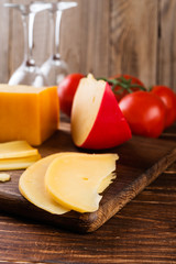 Cheese assortment and tomates on a on wooden background, selective focus